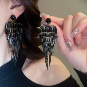 Close-up of elegant black tassel earrings with crystals on a female model