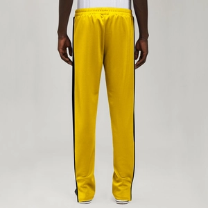 Detail view of bright yellow men's joggers with black side stripes and elastic waist