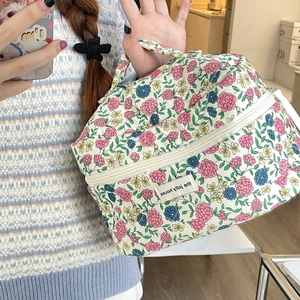 Close-up of quilted floral cosmetic bag featuring a secure double zipper and fabric handle
