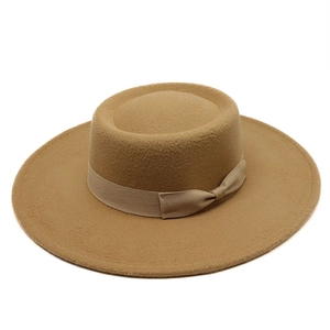 Detail of elegant camel wool boater hat featuring matching grosgrain ribbon and side bow