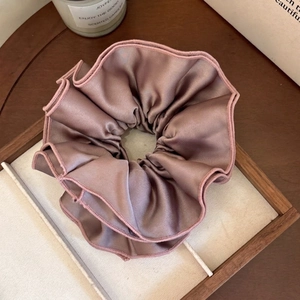 Detailed macro view of a large pleated silk satin scrunchie in elegant mauve purple color