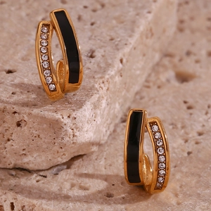 Macro detail of 18K gold plated U-shaped earrings with black enamel and micro inlay crystals