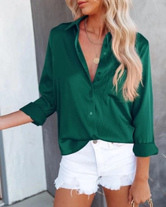 Détail de la texture satinée vert foncé lisse sur une chemise à manches longues
