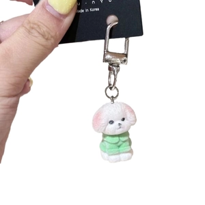 Mini white flocked bichon puppy keychain wearing a green sweater with metal buckle