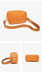 Detail of orange quilted crossbody camera bag showing gold leaf zipper and nylon strap