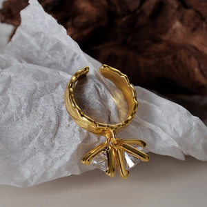 Macro detail of gold hammered sterling silver ring with three clear gemstone pendants