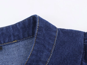 Détail du col d'une chemise en jean bleu foncé avec doubles surpiqûres nettes contrastées