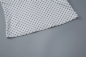 Macro detail of high-quality sewing on white fabric with classic black polka dots