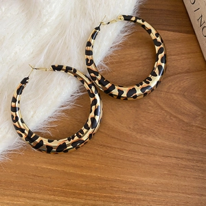 Detailed view of leopard print hoop earrings with a gold base and glossy animal pattern