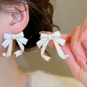 Elegant white enamel bow earrings with gold-plated trim in a delicate ribbon design