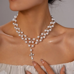 Détail d'un collier de perles à plusieurs rangs avec pendentif croix en zircon brillant