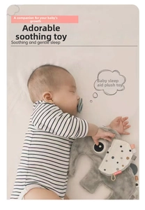 Close-up of a soft grey plush elephant security blanket held by a sleeping baby in bed