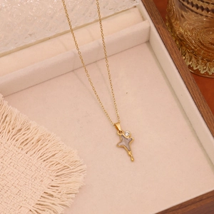 Detail of gold-plated cross star pendant necklace with cubic zirconia on beige fabric