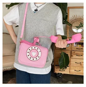 Detailed view of creative pink retro telephone shaped crossbody bag worn by a model