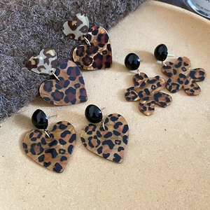 Detailansicht der Acryl-Ohrringe mit Leopardenmuster in Herzform auf beige Tablett