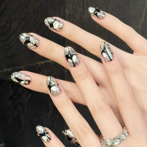 Galaxy silver cat eye press-on nails with black stars and metallic studs on dark wood