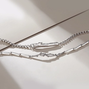 Silver double-layered bracelet with thorn and twig charms on Cuban and geometric chains