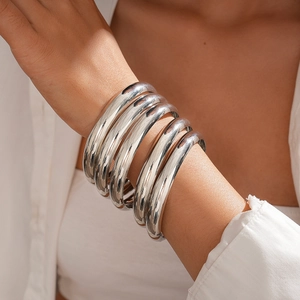 Macro detail of silver polished metal bangles layered set with high mirror gloss finish