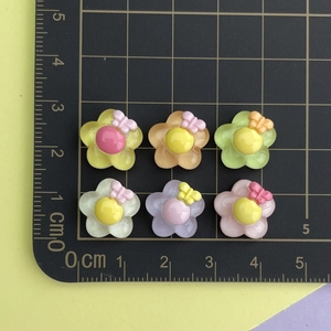 Detailed view of colorful resin flower charms with bows and gems for DIY nail art and crafts