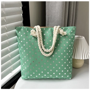 Green tote bag with white polka dots and thick rope handles shown in a sunny window setting