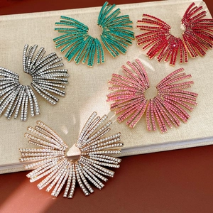 Macro shot of five luxury fan-shaped rhinestone earrings in various colors on a linen book