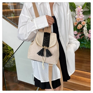 Detail of beige straw backpack with black tassels and woven texture for summer beach