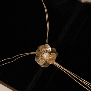 Gros plan du pendentif feuille de ginkgo dorée avec perle et texture en métal brossé