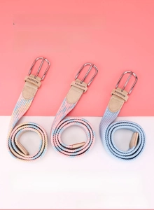 Close-up of three woven elastic belts with silver pin buckles and fashion embossed leather