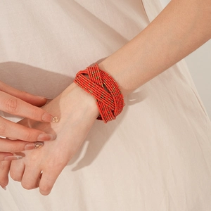 Détail d'un bracelet ethnique tissé à plusieurs couches de perles de verre rouge et or