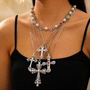 Detail of layered silver necklaces with pearl accents and varied cross pendants on model