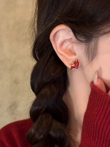 Close-up of red and gold dragon stud earrings with enamel finish on a model's ear
