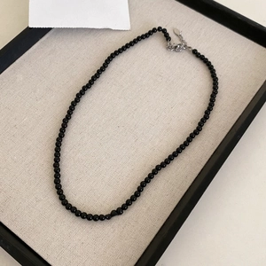 Detailed close-up of a black beaded necklace with silver clasp on a display tray