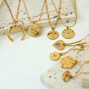 Detailed close-up of vintage gold necklaces with colorful zircon pendants on stone base