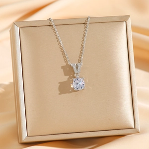 Silver V-letter pendant necklace with round zircon on a golden jewelry box