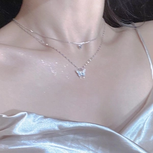 Detail of elegant silver butterfly layered necklace on model collarbone area