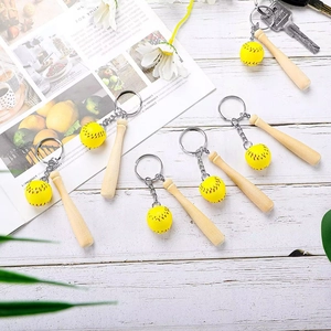 Close-up of mini wooden baseball bat keychain with stitched yellow ball on white wood
