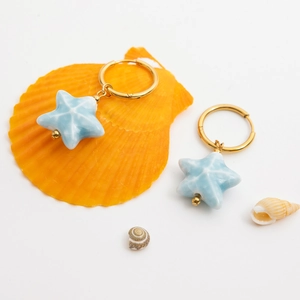 Close-up of blue starfish earrings with 18K gold-plated hoops and sea shell accents