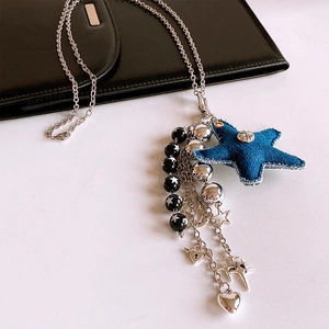 Détail des pendentifs étoiles en denim et perles argentées sur un collier en acier chic