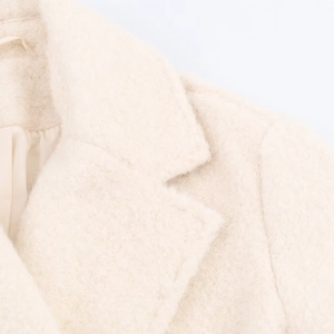 Detail shot of ivory boucle wool coat collar showing plush texture and satin lining