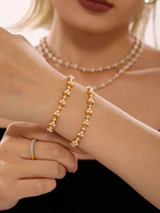 Close-up of elegant gold plated bracelet featuring white shell pearls on a model wrist