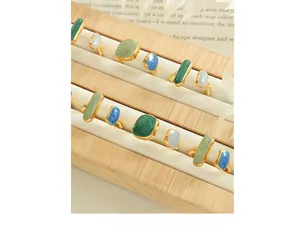 Detail view of gold-plated adjustable rings with colorful enamel gemstones on display