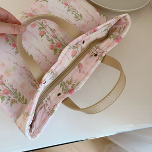 Close-up of floral tote bag featuring a secure zipper closure and premium leather handles
