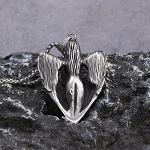 Detailed close-up of retro silver angel wing necklace pendant on a dark stone texture