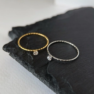 Macro detail of minimalist ripple textured gold and silver rings with sparkling zircon stones