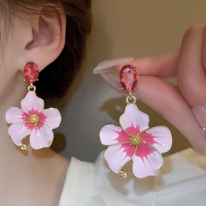 Detailed view of vintage pink flower earrings with red gemstone and gold edges