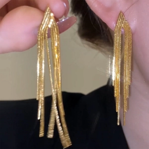 Macro detail of long gold metal fringe earrings with multi-strand tassel design