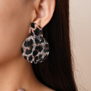 Close-up of leopard print acrylic geometric drop earrings worn by a model in profile
