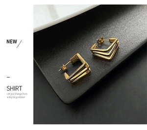 Detail view of gold titanium geometric U-shaped earrings with layered minimalist design