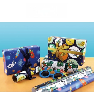 Close-up of space and dinosaur wrapping paper rolls with Happy Birthday party glasses