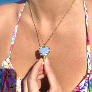 Barbie style gold heart mirror necklace with blue enamel and floral charms on model